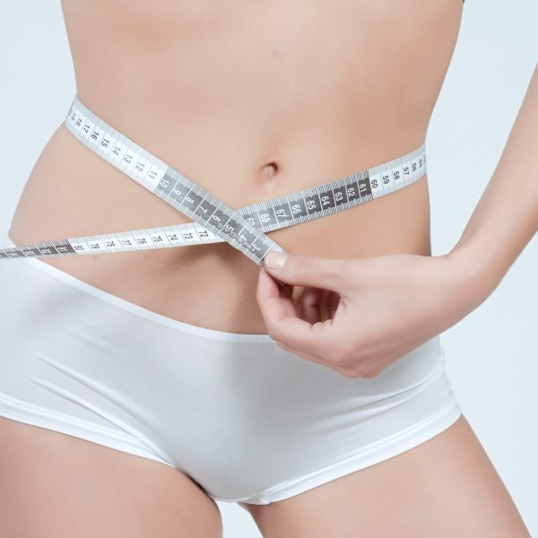 femme mesurant son ventre plat en boxer blanc